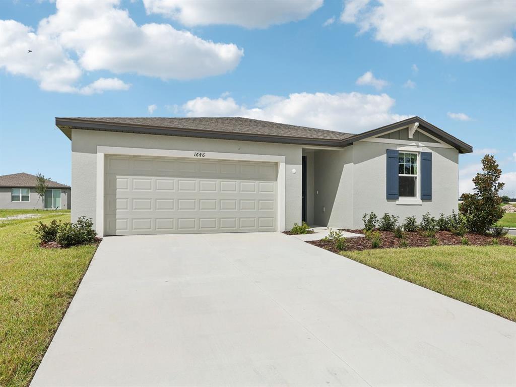A single-story house with a beige stucco exterior, a two-car garage, and blue shutters — 1646 BARK RIDGE DRIVE, AUBURNDALE, FL