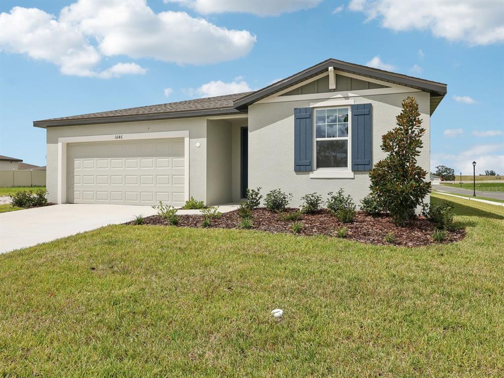 A single-story house with a beige stucco exterior, a two-car garage, and blue shutters — 1646 BARK RIDGE DRIVE, AUBURNDALE, FL