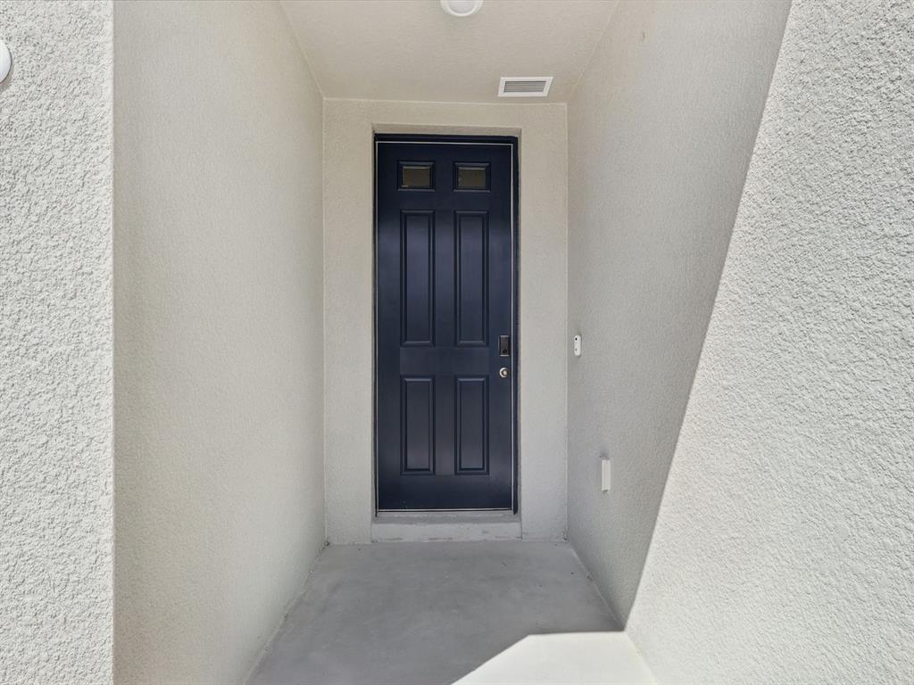 A dark blue front door is set within a recessed, light-colored stucco entryway — 1646 BARK RIDGE DRIVE, AUBURNDALE, FL