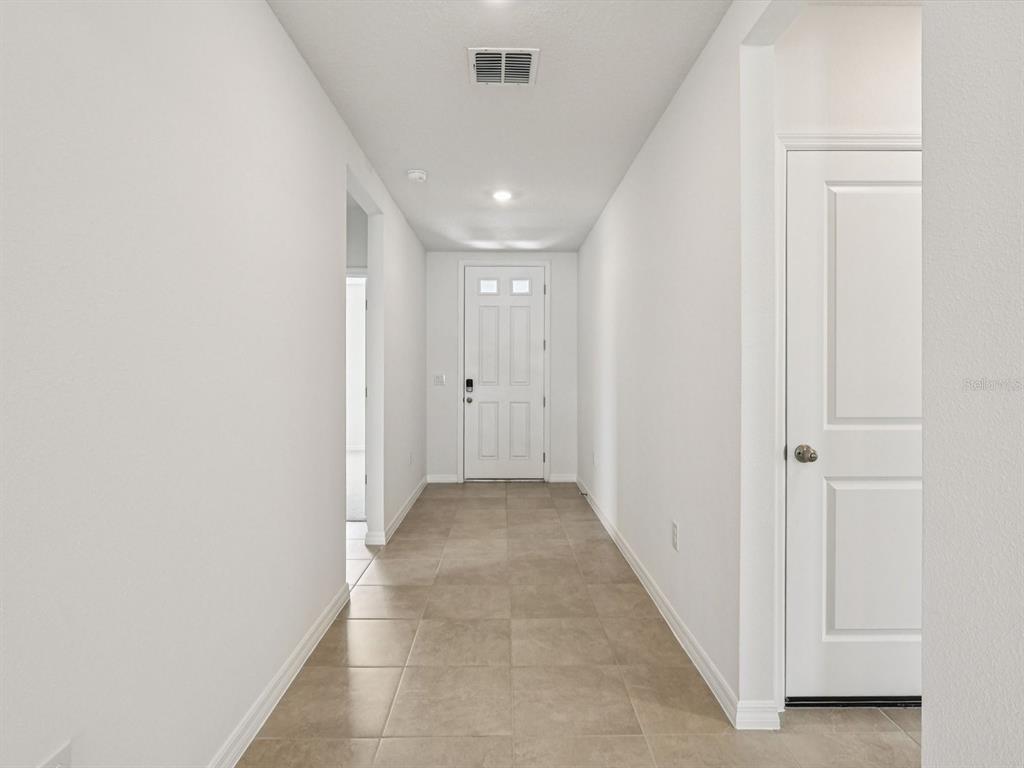 A bright entryway features light-colored tile flooring, white walls, and a white front door — 1646 BARK RIDGE DRIVE, AUBURNDALE, FL