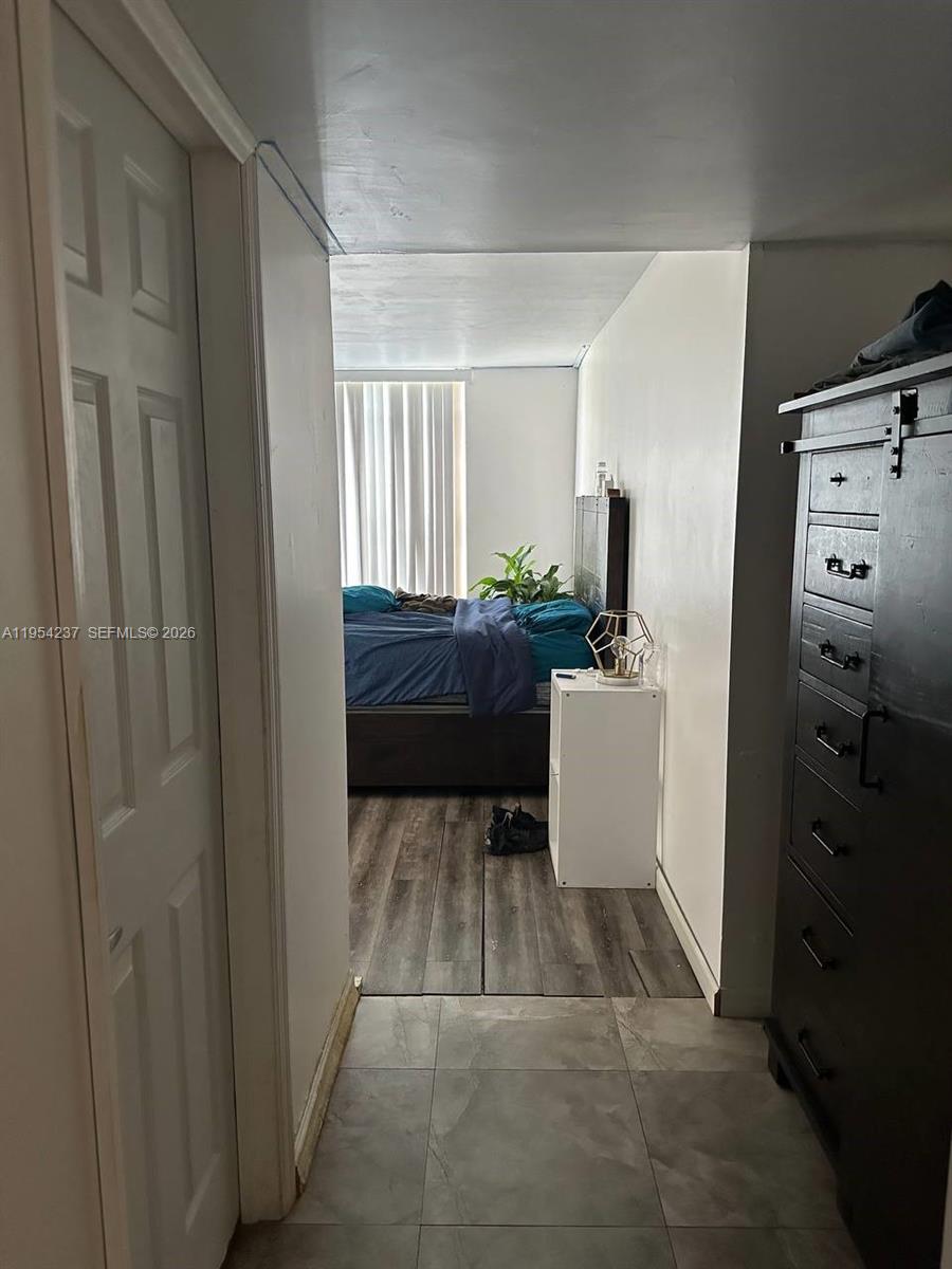 A view from a tiled hallway looking into a bedroom with wood-look flooring — 3720 Inverrary Dr # 1L, Lauderhill FL 33319, LAUDERHILL, FL