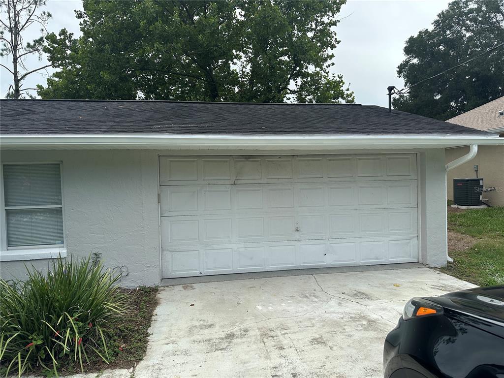 A white garage door is attached to the side of a gray stucco house — 13678 SE 55TH AVENUE, SUMMERFIELD, FL