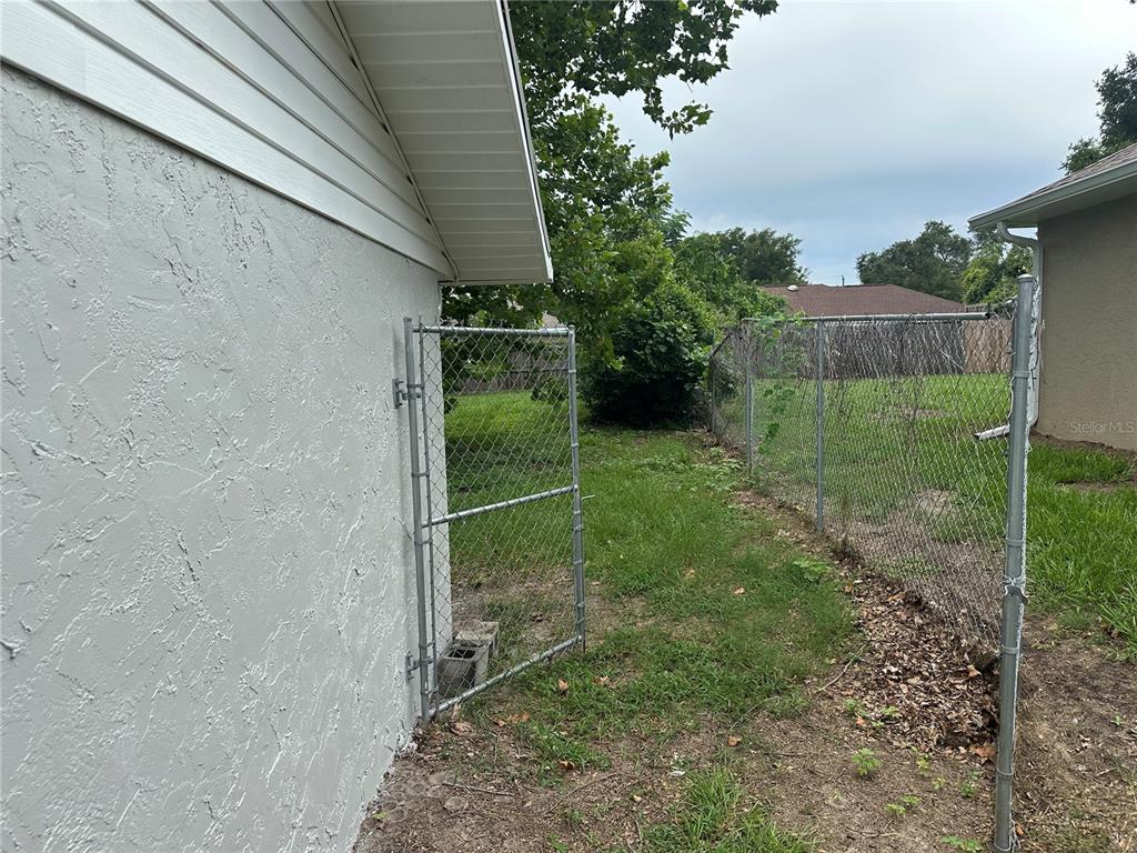 A side yard features a chain-link fence, a gate, and a patch of grass — 13678 SE 55TH AVENUE, SUMMERFIELD, FL