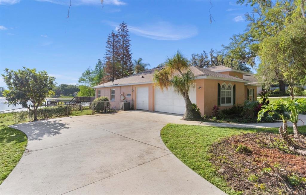 A peach-colored house with a two-car garage and a concrete driveway near a lake — 9440 COUNTY ROAD 561, CLERMONT, FL
