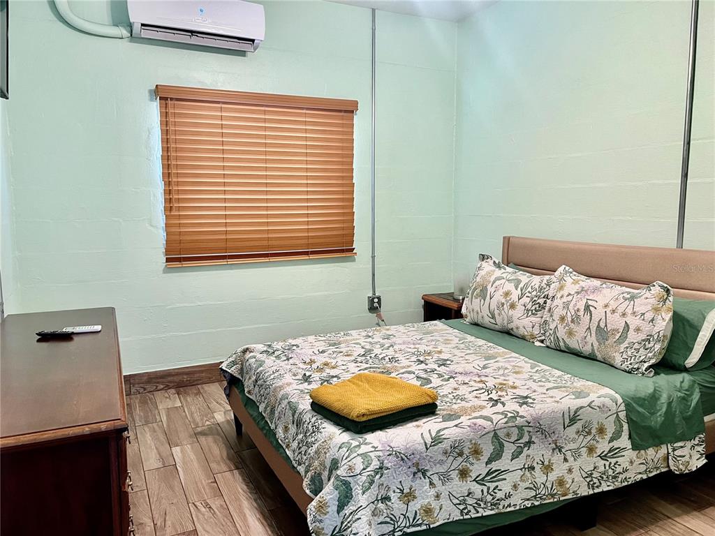 A bedroom features light green walls, a bed with floral bedding, and wood-look tile flooring — 821 MULBERRY STREET UNIT D, MAITLAND, FL