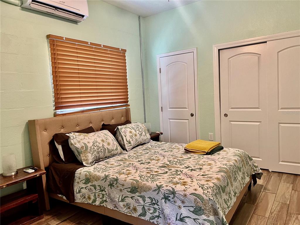 A bedroom features a bed with floral bedding, light green walls, and two white doors — 821 MULBERRY STREET UNIT D, MAITLAND, FL