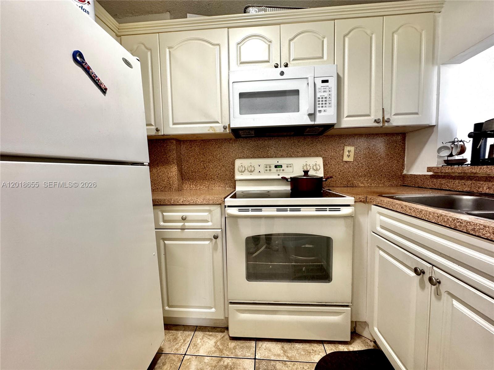 A kitchen features white cabinets, white appliances, and speckled brown countertops — 8145 NW 7th St # 404, Miami FL 33126, MIAMI, FL