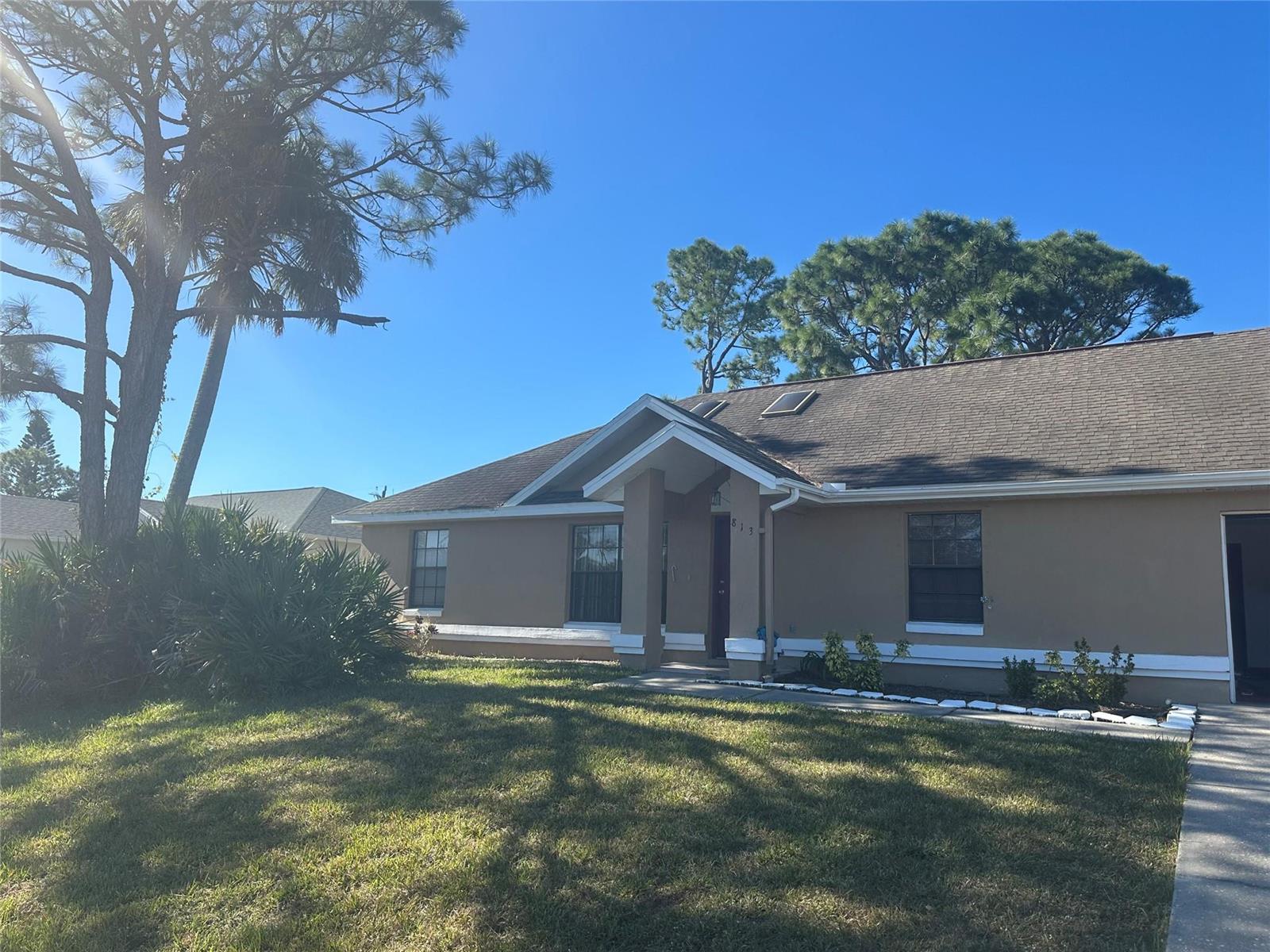 A tan single-story house with a gabled entryway, dark roof, and a large pine tree — 813 Seven Gables Circle, Palm Bay FL 32909, PALM BAY, FL