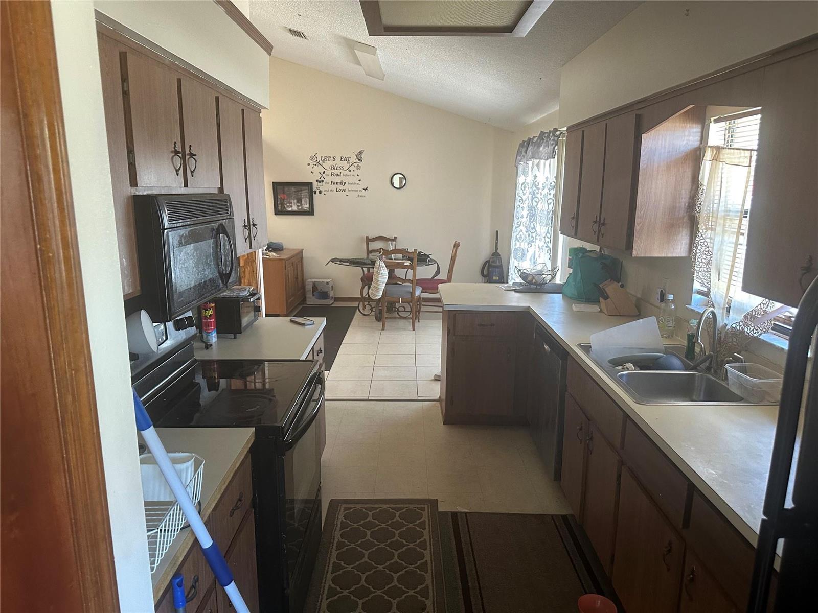 A kitchen with brown cabinets, laminate countertops, and a dining area in the background — 813 Seven Gables Circle, Palm Bay FL 32909, PALM BAY, FL