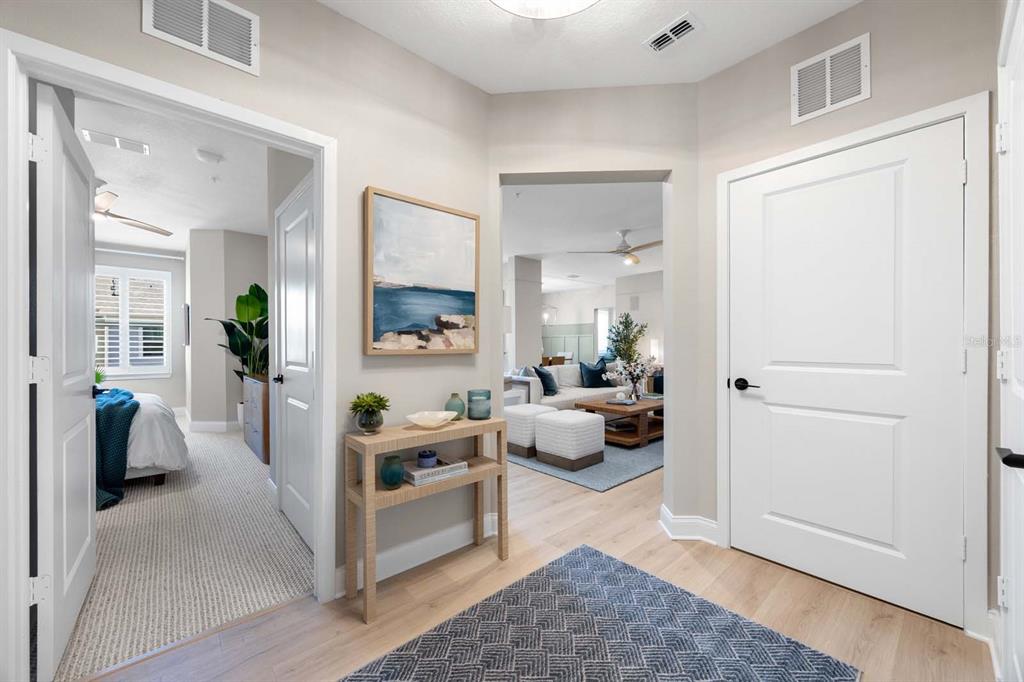 A bright entryway features light wood floors, a console table, and views into adjacent rooms — 7557 LAUREATE BOULEVARD UNIT 6407, ORLANDO, FL