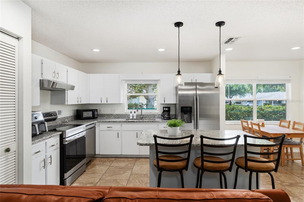 A kitchen features white cabinets, granite countertops, stainless steel appliances, and a central island — 9755 SW 94TH TERRACE UNIT D, OCALA, FL