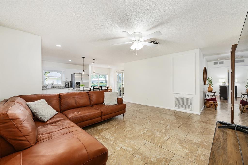 A living room with a brown leather sectional, tile flooring, and an open kitchen — 9755 SW 94TH TERRACE UNIT D, OCALA, FL
