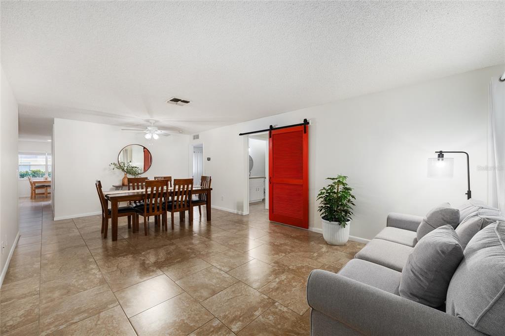 A living and dining room features light tile floors, a red barn door, and gray sofa — 9755 SW 94TH TERRACE UNIT D, OCALA, FL