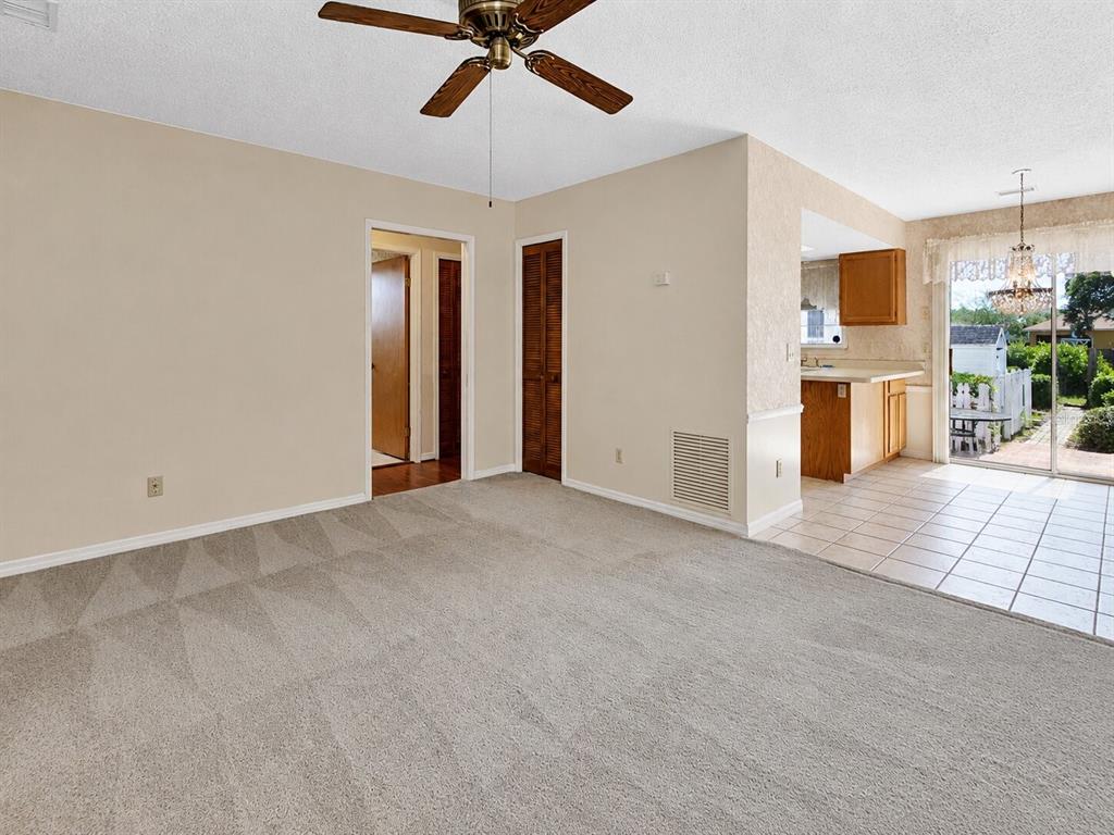A carpeted living room opens to a tiled kitchen and a sliding glass door — 1141 8TH AVENUE, DELAND, FL