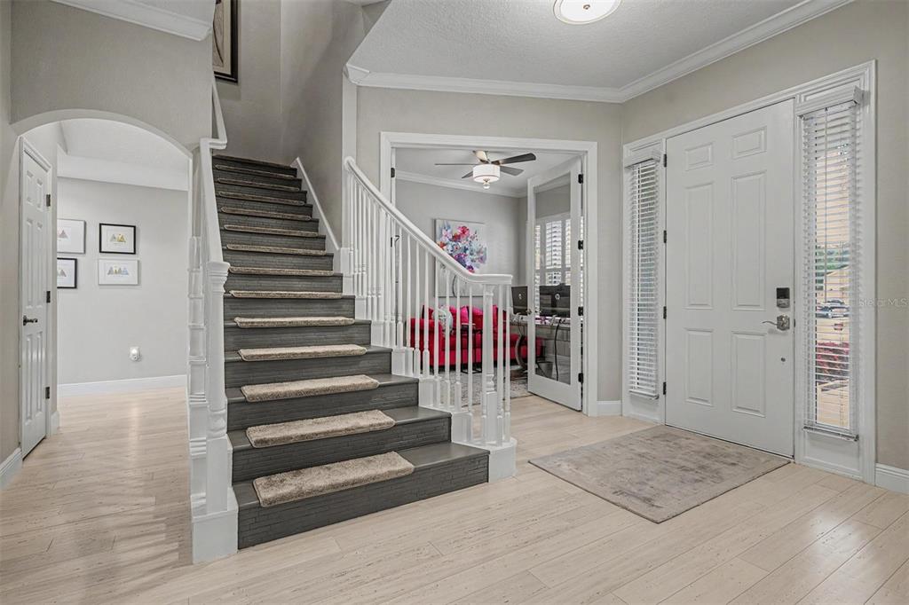 An entryway features a staircase with dark treads and carpet runners, light wood flooring, and French doors — 5116 ABISHER WOOD LANE, BRANDON, FL