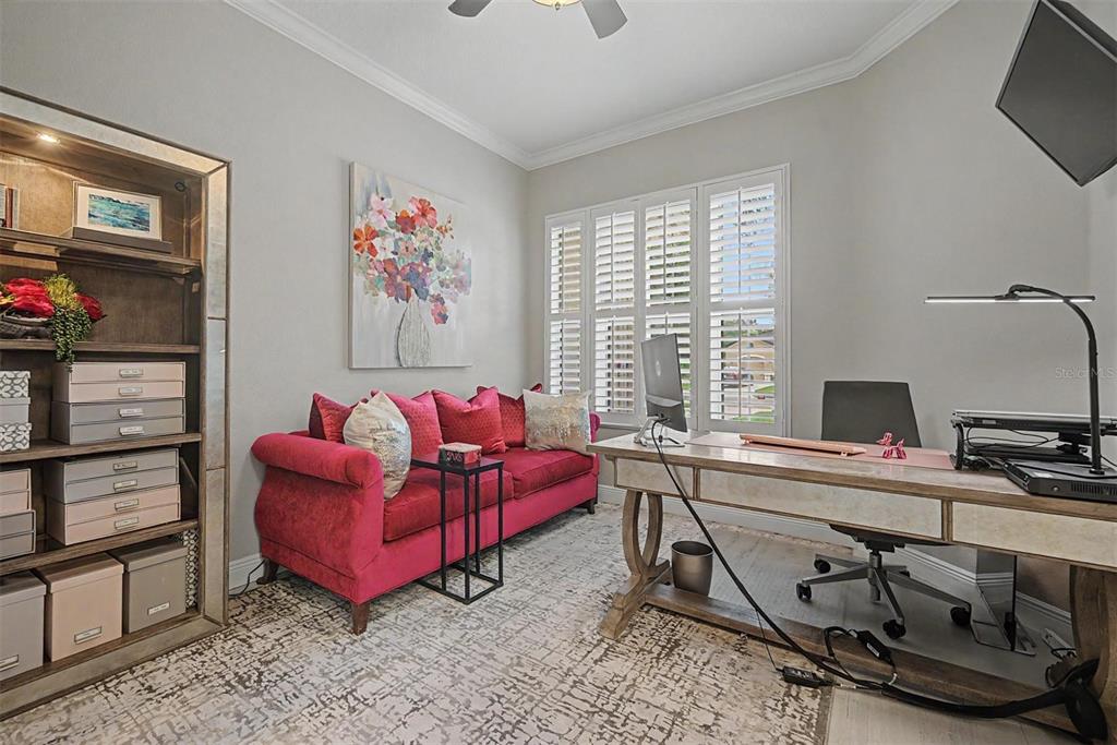 A home office features a pink sofa, a wooden desk, and a tall shelving unit — 5116 ABISHER WOOD LANE, BRANDON, FL