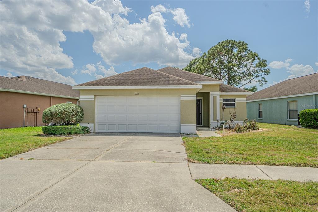 A single-story house with a two-car garage, light-colored stucco walls, and a concrete driveway — 5553 GALLANT FOX COURT, WESLEY CHAPEL, FL