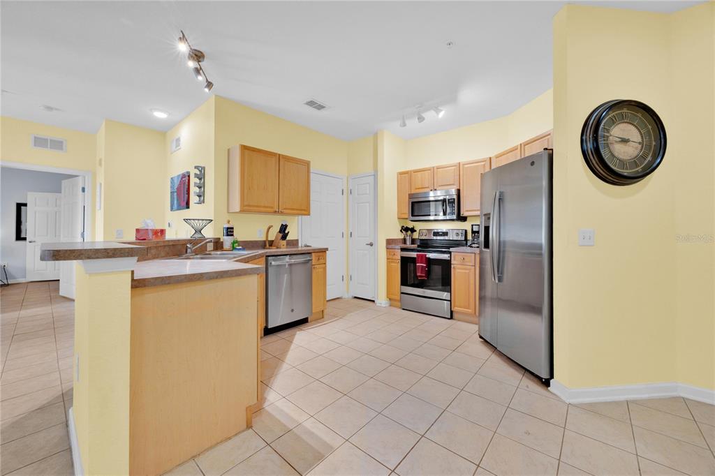 A kitchen with light yellow walls, wood cabinets, stainless steel appliances, and tile flooring — 804 TERRACE RIDGE CIRCLE UNIT 804, DAVENPORT, FL