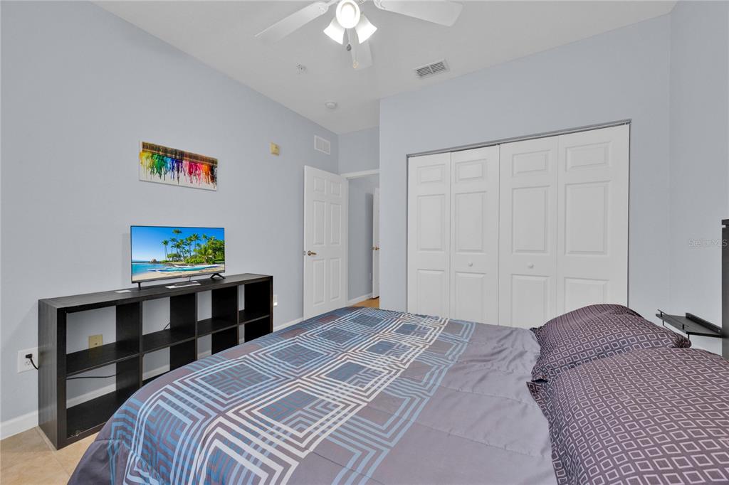 A bedroom features a bed, a black media console with a television, and white closet doors — 804 TERRACE RIDGE CIRCLE UNIT 804, DAVENPORT, FL