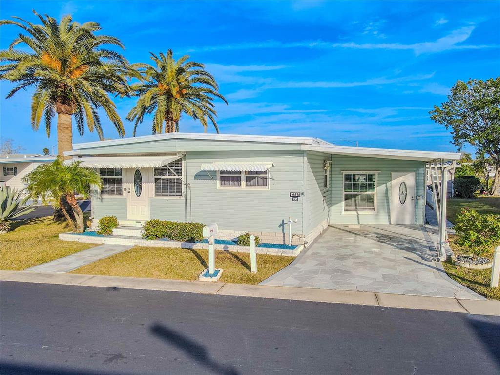 An aerial view shows a manufactured home community with a canal and a large lake — 10343 MAGNOLIA LANE UNIT 180, LARGO, FL