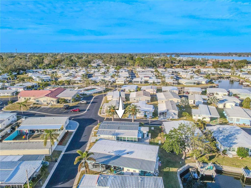 A light blue manufactured home features a palm tree, a paved driveway, and a carport — 10343 MAGNOLIA LANE UNIT 180, LARGO, FL