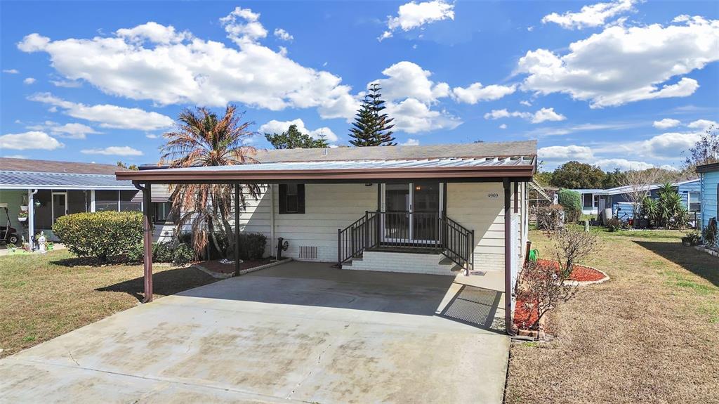 A single-story house with a carport, concrete driveway, and a small front porch with railings — 4969 DEERWOOD DR, LAKELAND, FL