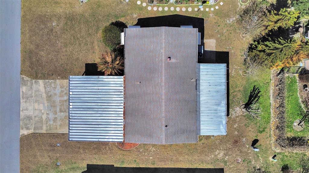 An aerial view shows a house with a shingled roof and two metal-covered sections — 4969 DEERWOOD DR, LAKELAND, FL