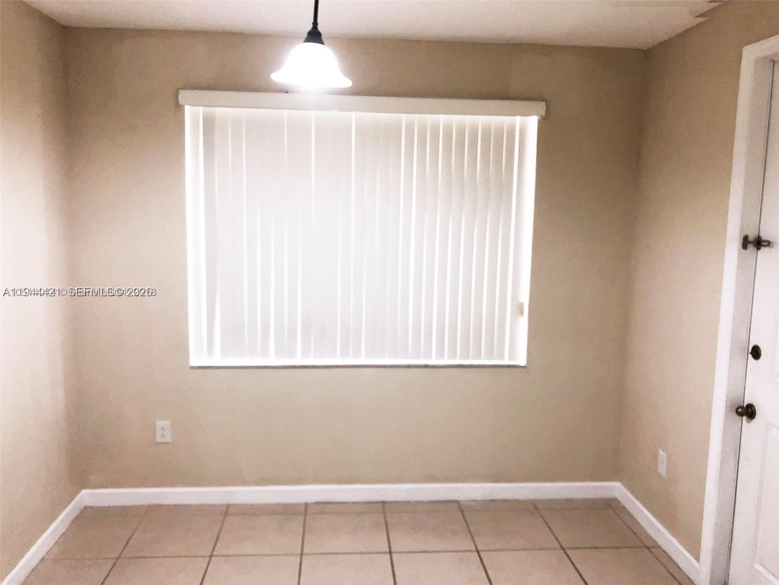 A room with beige walls, tile flooring, a window with vertical blinds, and a pendant light — 2884 SE 2 Dr # 2, Homestead FL 33033, HOMESTEAD, FL