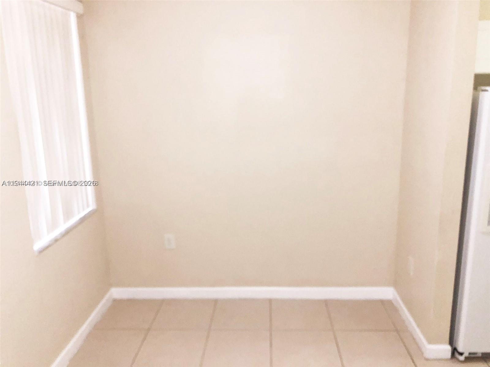 An empty room with beige walls, light-colored tile flooring, and a window with vertical blinds — 2884 SE 2 Dr # 2, Homestead FL 33033, HOMESTEAD, FL