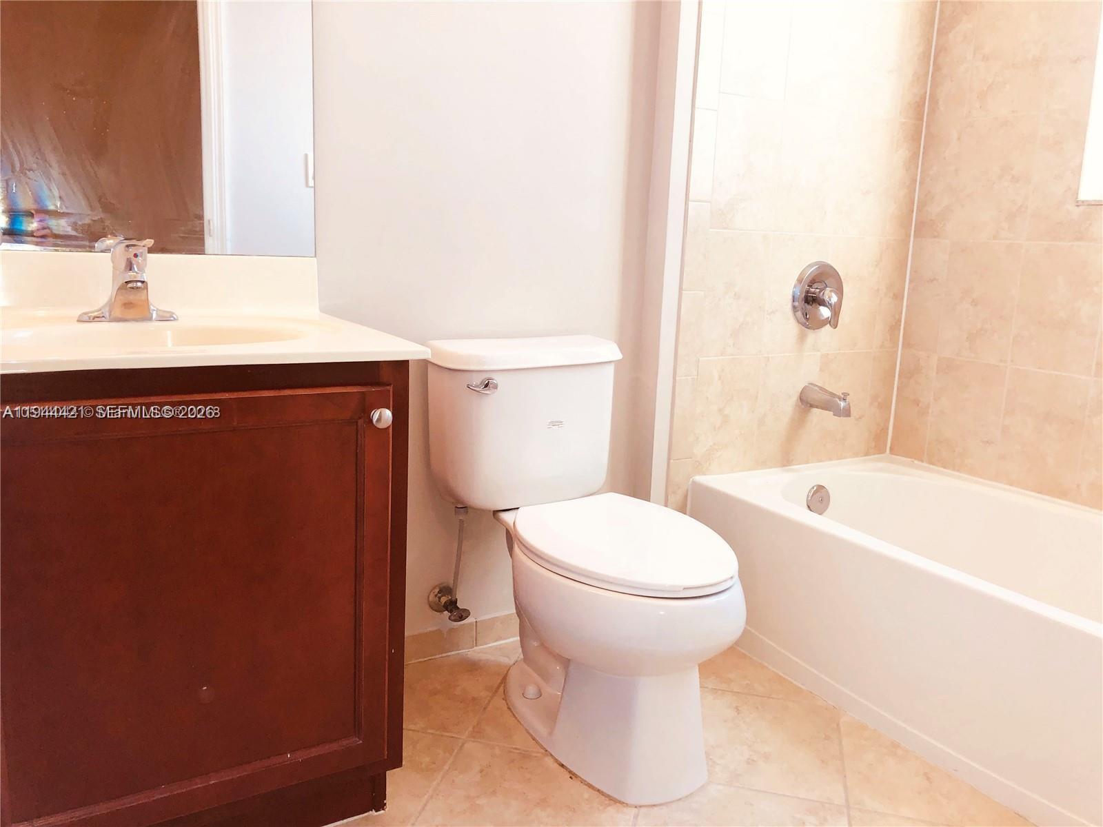 A bathroom features a dark wood vanity, a white toilet, and a tiled bathtub surround — 2884 SE 2 Dr # 2, Homestead FL 33033, HOMESTEAD, FL
