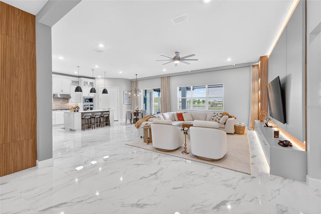 An open-concept living room and kitchen featuring white marble floors and a large sectional sofa — 13207 PANAMA BEACH COURT, ORLANDO, FL