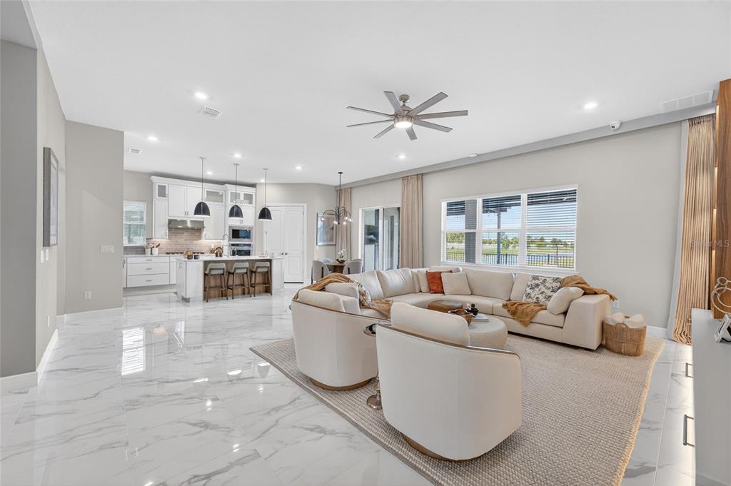 An open-concept living room and kitchen featuring white marble floors and a large sectional sofa — 13207 PANAMA BEACH COURT, ORLANDO, FL