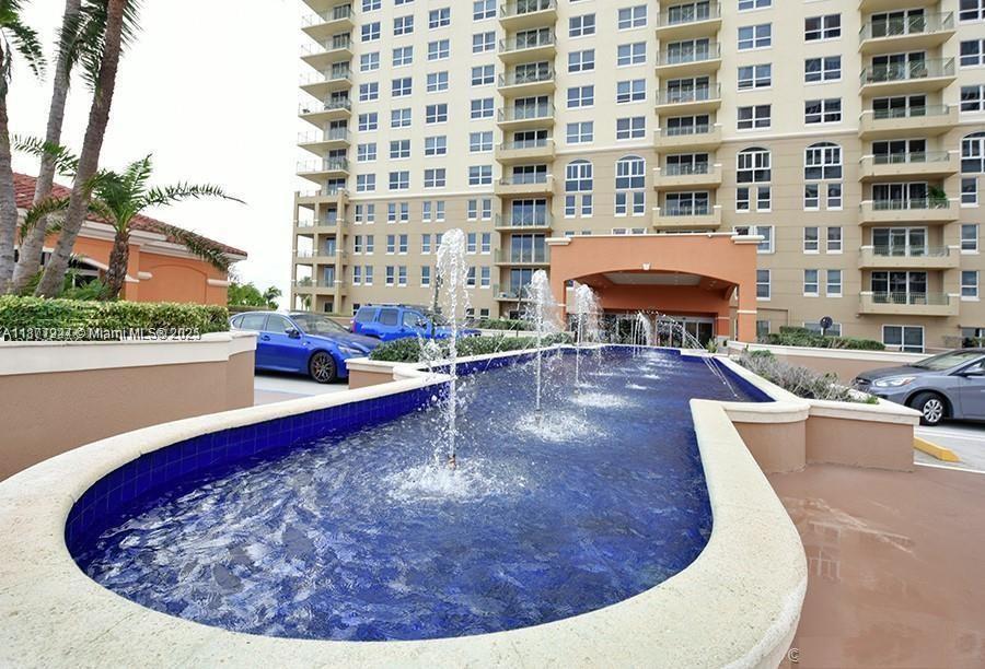 A blue tiled fountain with multiple water jets sits in front of a tall apartment building — 2080 S Ocean Dr # 1507, Hallandale Beach FL 33009, HALLANDALE BEACH, FL