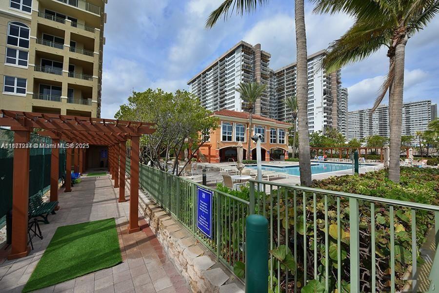 A swimming pool area with a pergola, lounge chairs, and surrounding high-rise residential buildings — 2080 S Ocean Dr # 1507, Hallandale Beach FL 33009, HALLANDALE BEACH, FL