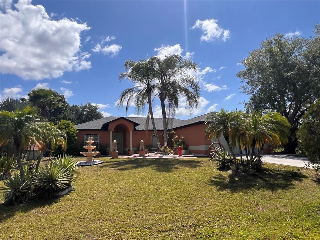 A single-story house with a terracotta exterior, palm trees, and a front yard fountain — 3900 OAK POINTE BOULEVARD, KISSIMMEE, FL