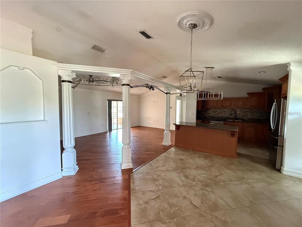 An open-concept kitchen with tile flooring transitions into a living area with wood floors — 3900 OAK POINTE BOULEVARD, KISSIMMEE, FL