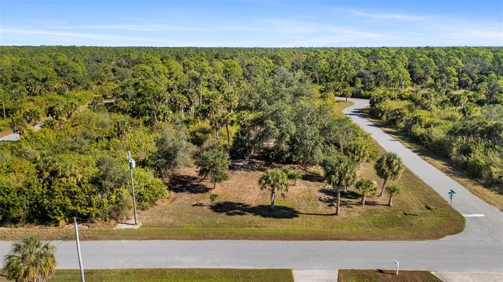 An aerial view shows a vacant, wooded residential lot situated at a street corner — 1335 CAPTAN TERRACE, PORT CHARLOTTE, FL