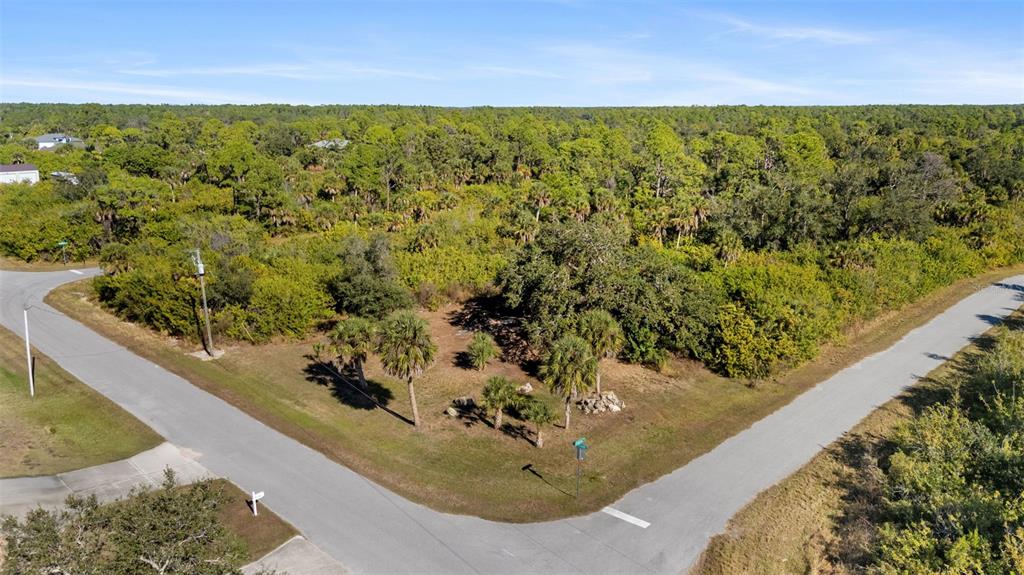 An aerial view shows a vacant, wooded corner lot at the intersection of two roads — 1335 CAPTAN TERRACE, PORT CHARLOTTE, FL