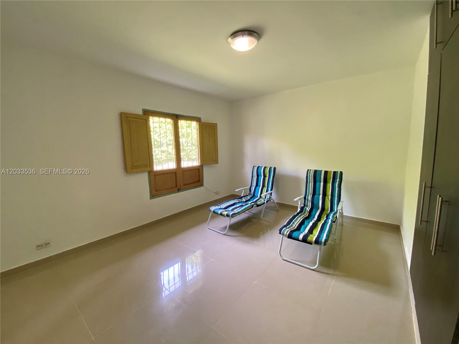 An empty room with light tile floors, white walls, a window, and two lounge chairs — Casa 21 Barrio Morelia, FL, FL