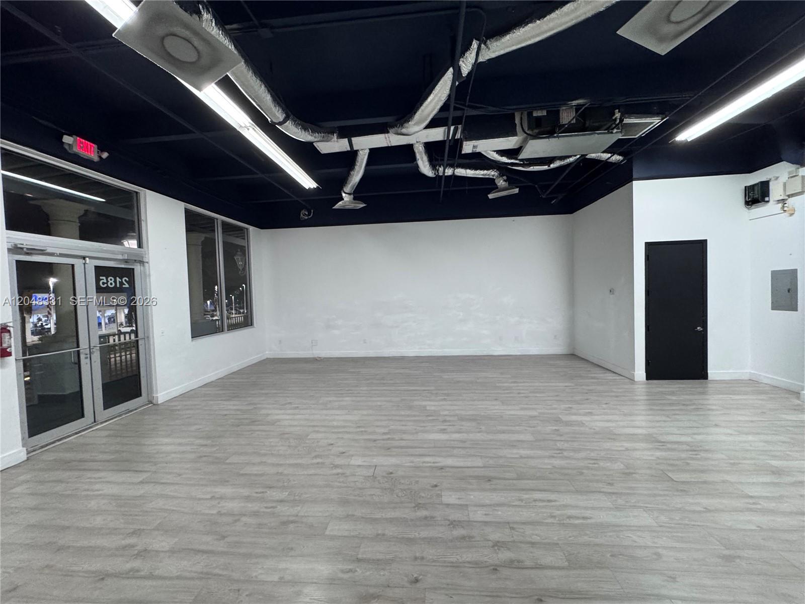 An empty commercial space features a dark ceiling, exposed ductwork, white walls, and light flooring — 2185 NE 163rd St, North Miami Beach FL 33162, NORTH MIAMI BEACH, FL