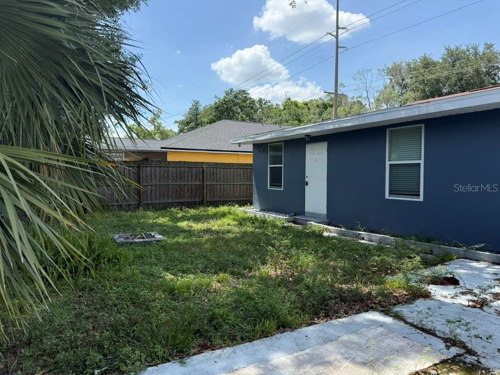 A blue house exterior features a white door and windows next to a grassy yard — 1512 W KIRBY STREET, TAMPA, FL