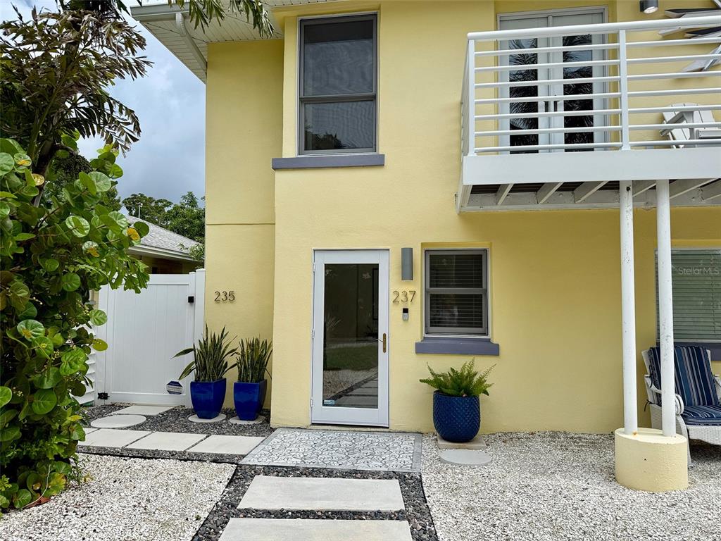 A yellow two-story building exterior features a white door, a balcony, and potted plants — 237 20TH AVENUE SE, ST PETERSBURG, FL