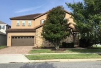 A two-story house with a brown garage, stone facade, and a tiled roof — 9240 WOODCRANE DRIVE, WINTER GARDEN, FL