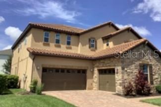 A two-story house with a tan stucco exterior, stone accents, and a two-car garage — 9240 WOODCRANE DRIVE, WINTER GARDEN, FL