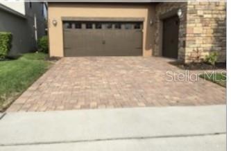 A two-story tan stucco house with a tile roof and palm trees on a sunny day — 9240 WOODCRANE DRIVE, WINTER GARDEN, FL