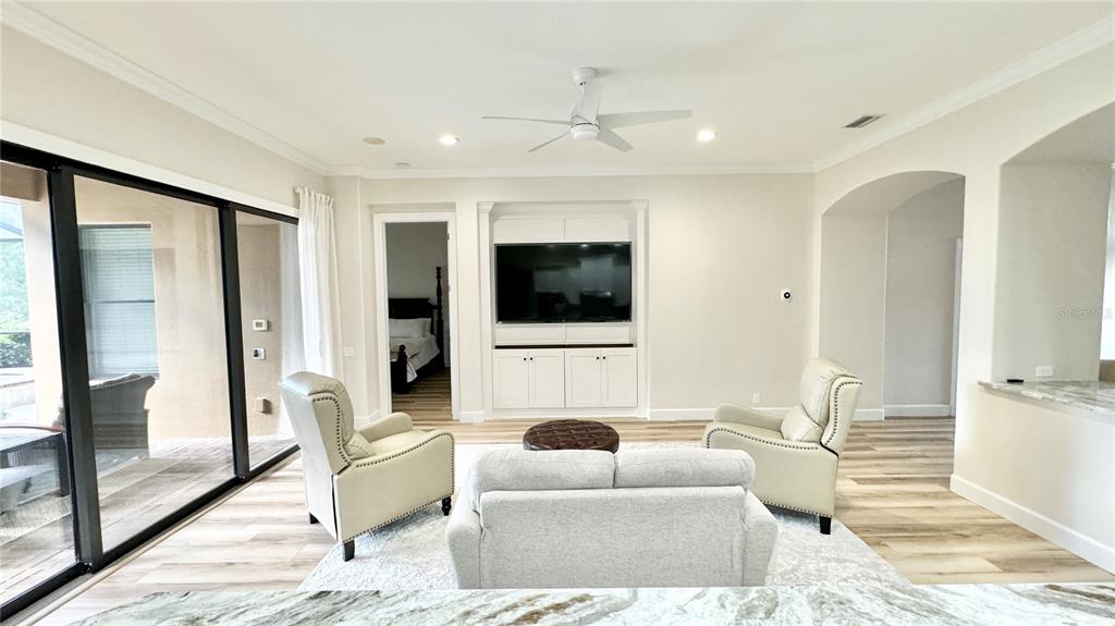 A living room features a built-in media center, two armchairs, a sofa, and sliding glass doors — 6752 SW 179TH AVENUE ROAD, DUNNELLON, FL