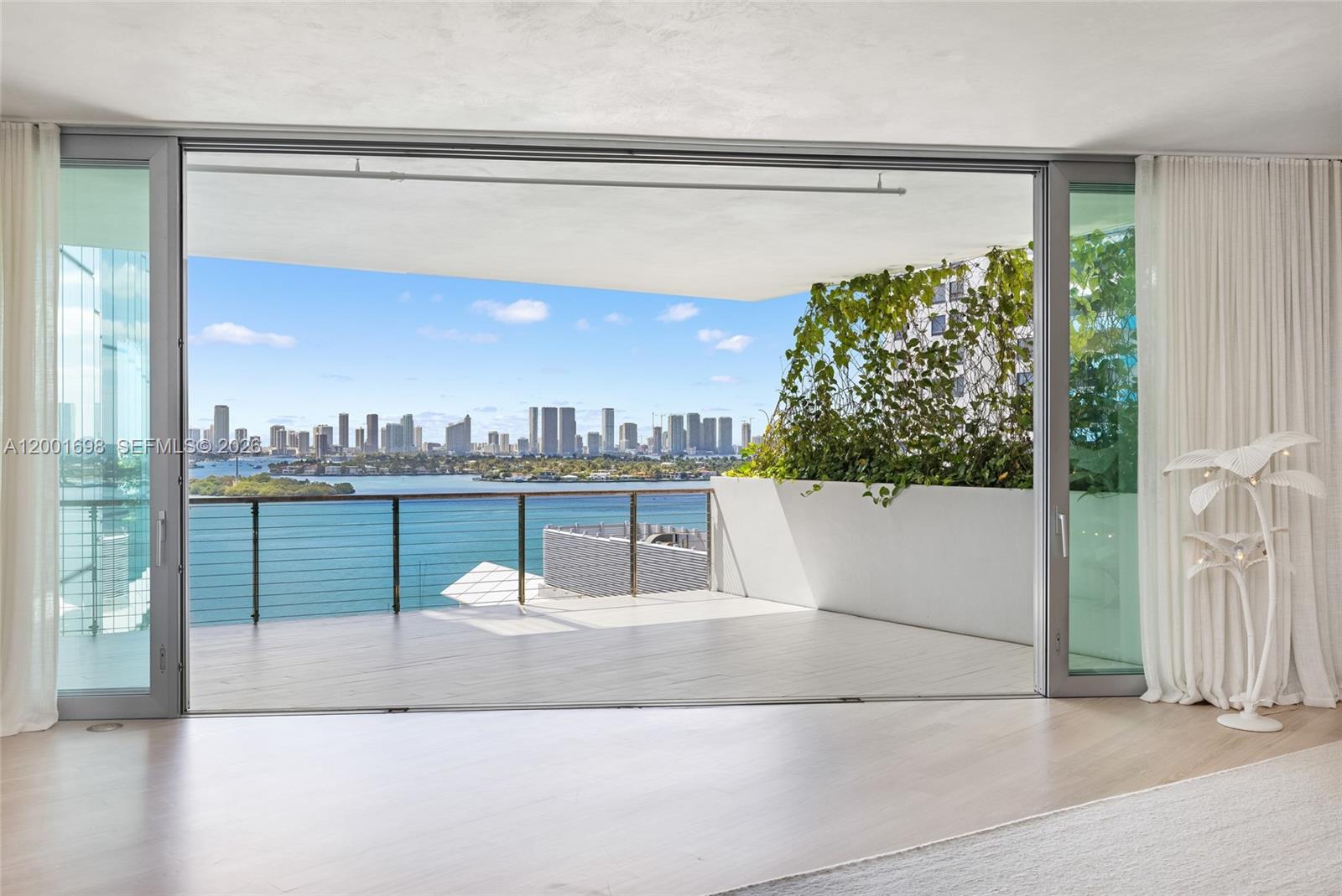 A bright room features large sliding glass doors opening onto a balcony with water views — 1300 Monad Ter # 11E, Miami Beach FL 33139, MIAMI BEACH, FL