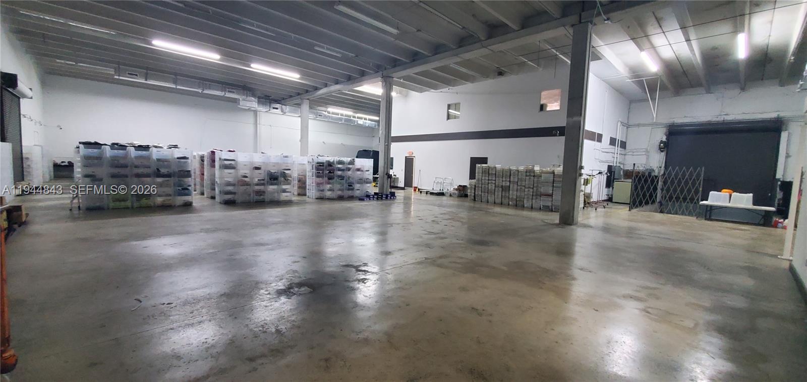 A large, open industrial warehouse space features concrete floors, exposed ceilings, and stacked storage bins — 2100 NW 93rd Ave, Doral FL 33172, DORAL, FL