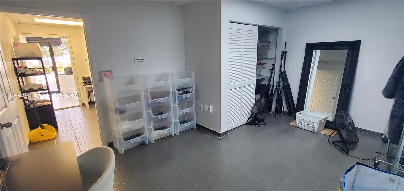 A room with gray tile flooring, white walls, storage bins, and a large black mirror — 2100 NW 93rd Ave, Doral FL 33172, DORAL, FL