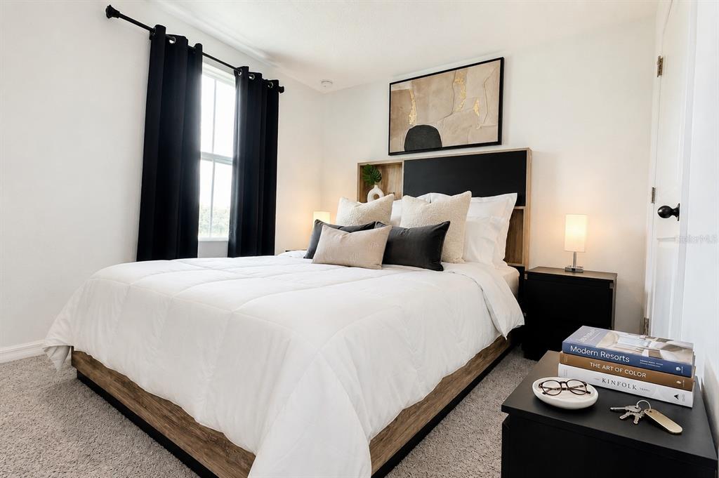 A bedroom features a bed with a white and wood headboard, gray bedding, and black curtains — 835 LONGBOAT DRIVE, DAVENPORT, FL